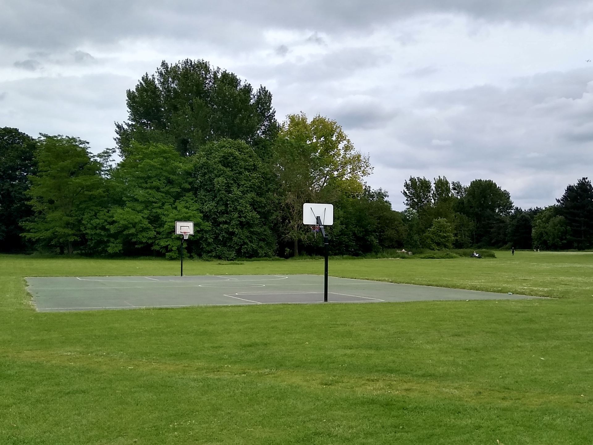 An empty outdoor basketball court with hoops on a clear day