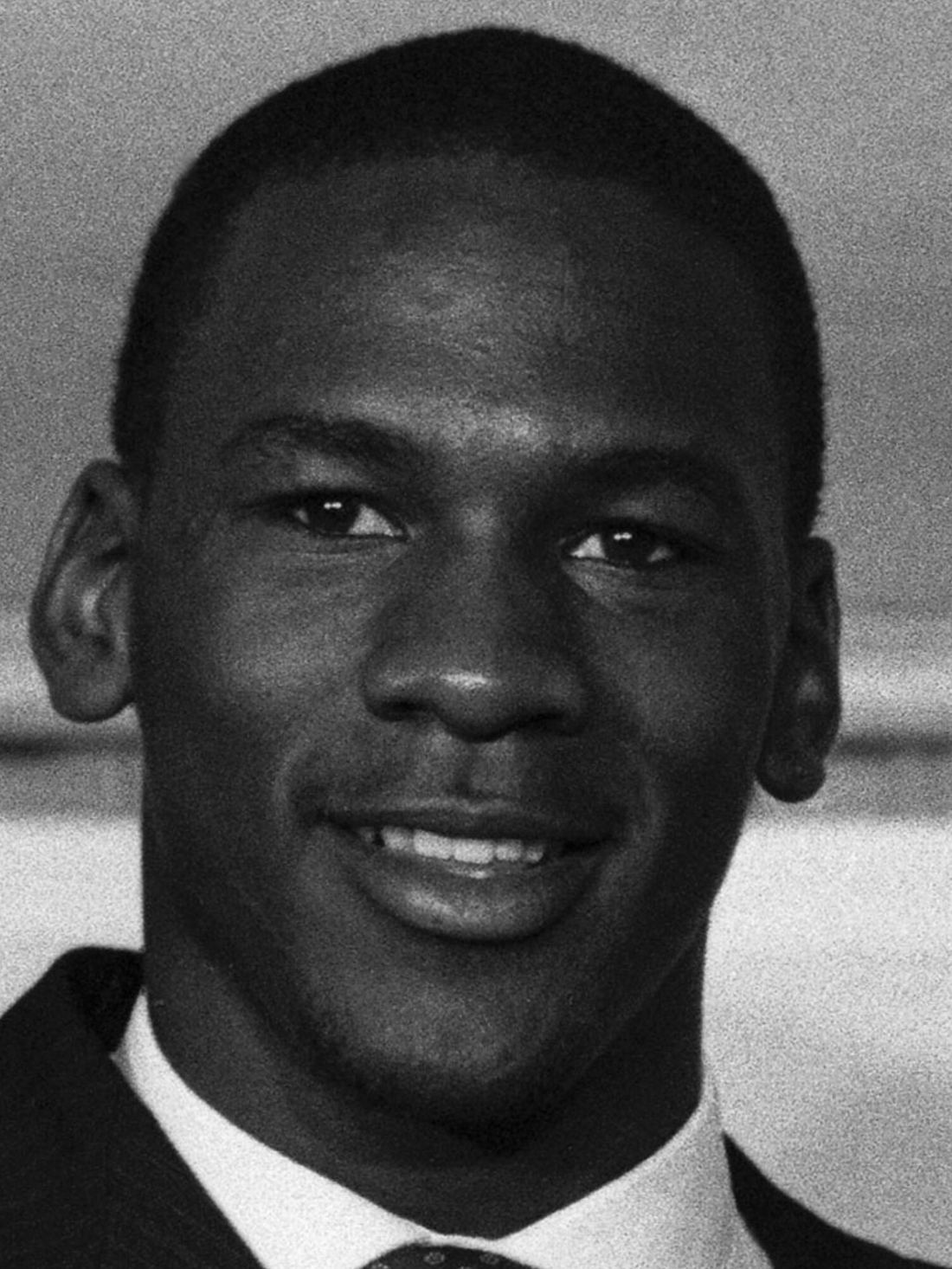 A young Michael Jordan holding up his new Chicago jersey in 1984
